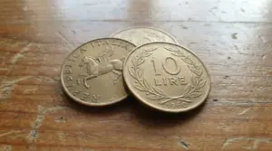 Monete da 10 lire del 1960 appoggiate su una superficie in legno