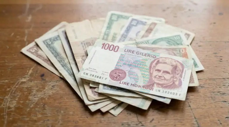 Vecchie banconote in lire italiane adagiate su un tavolo di legno