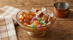 Caramelle assortite in una coppa di vetro su un tavolo rustico in legno