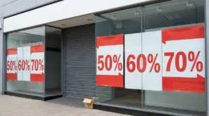 Vetrina di negozio vuoto con cartelli di saldi dal 50% al 70%