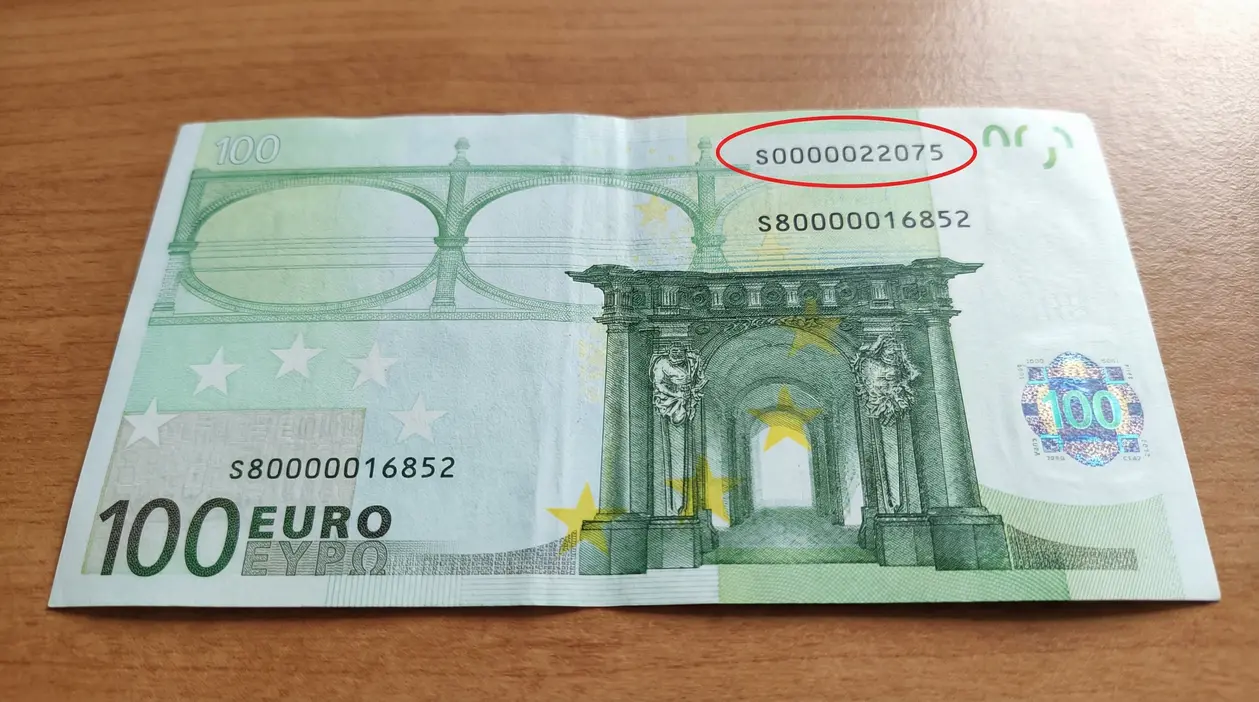 Banconota da 100 euro appoggiata su un tavolo con numero di serie visibile