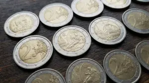 Diverse monete da due euro rare disposte su un tavolo in legno