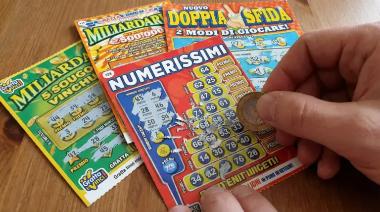 Una persona gratta un biglietto del Gratta e Vinci con una moneta su un tavolo.