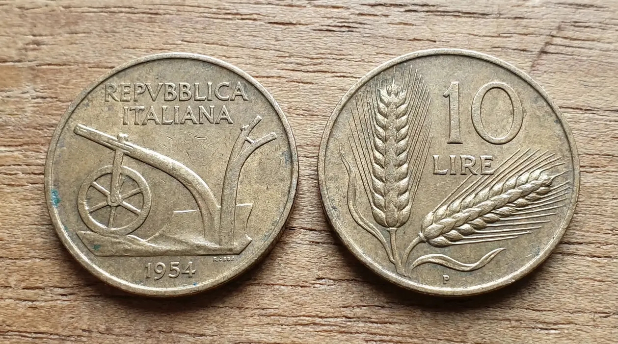 Vecchia moneta italiana da 10 lire con spiga e aratro su sfondo in legno