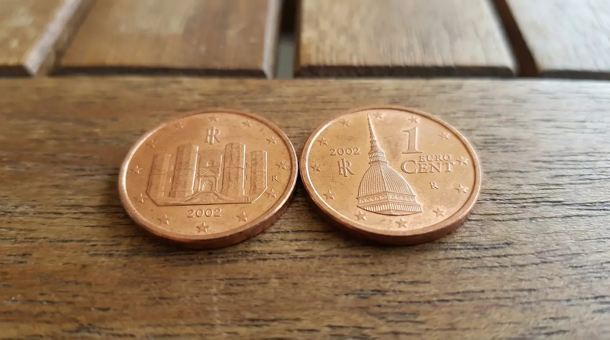 Due monete da 1 centesimo di euro su una superficie di legno.