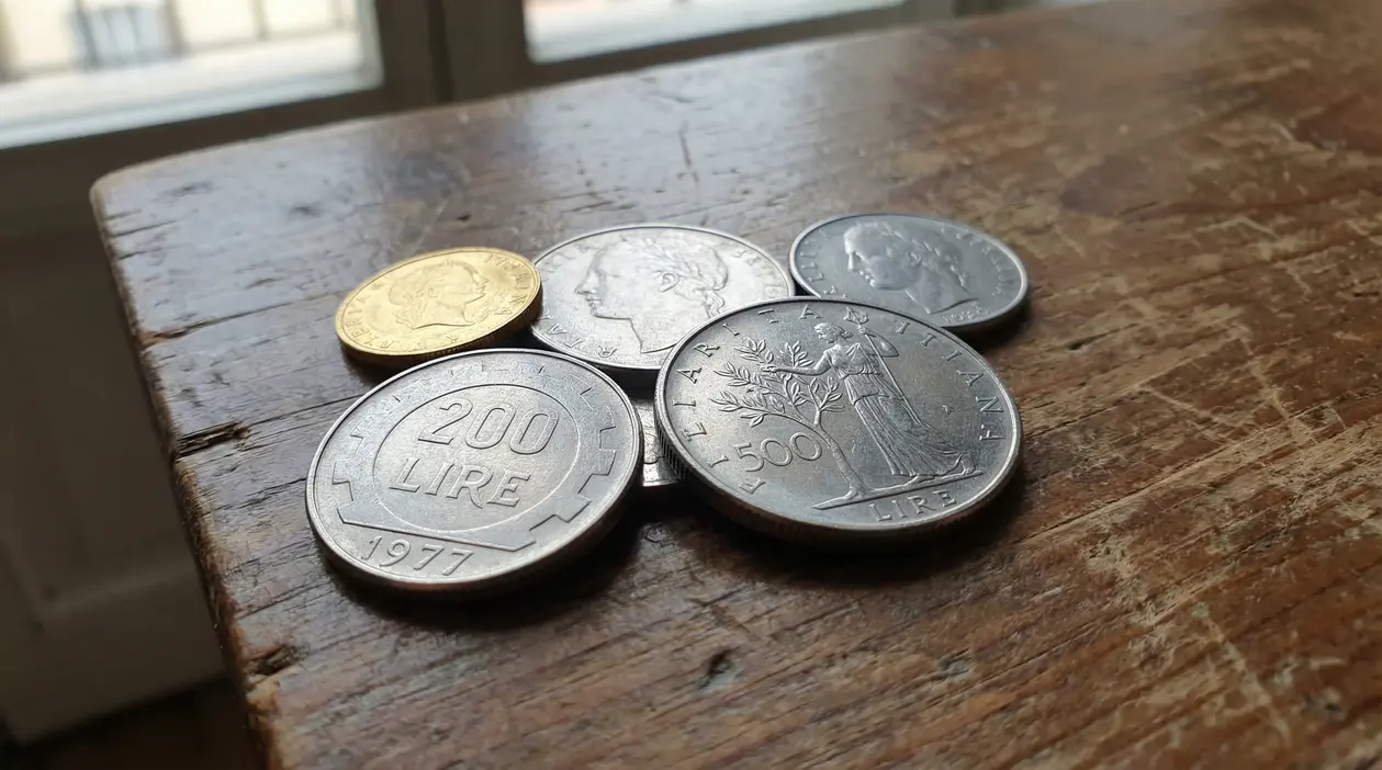 Vecchie monete italiane in Lire appoggiate su un tavolo di legno