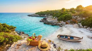 Piccola spiaggia tranquilla con barca in legno, mare cristallino e picnic al tramonto